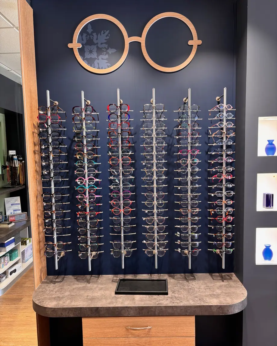 Un mur de montures, sous une paire de lunettes en bois découpé